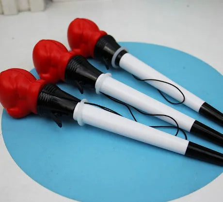 Set of four black pressure relief pens with a boxing press ejection mechanism on a desk.