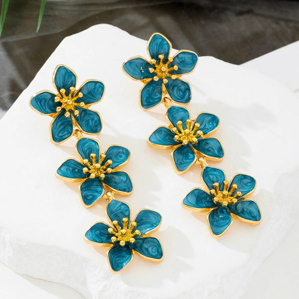 Oil dripping four petal flower earrings in orange resin on a white background