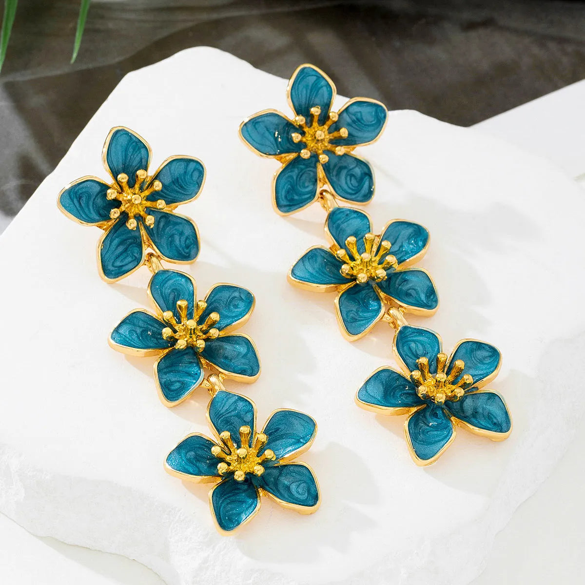 Oil dripping four petal flower earrings in orange resin on a white background