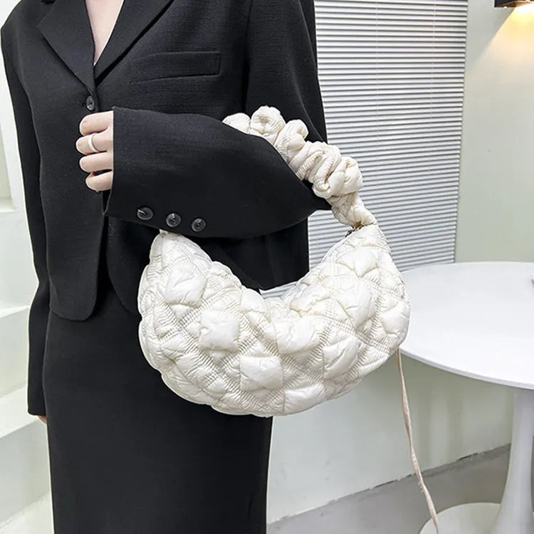 Women's light beige nylon cloud underarm messenger bag with a long adjustable shoulder strap.