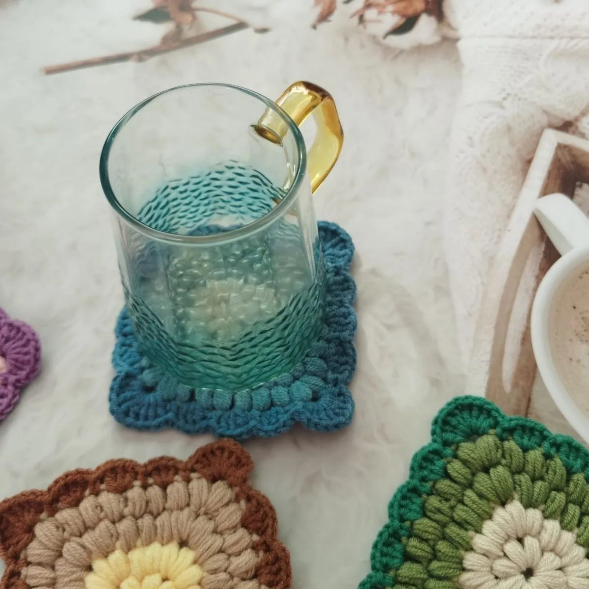 Hand-crocheted wool coaster with lattice pattern in Dream Purple colour on a wooden table.