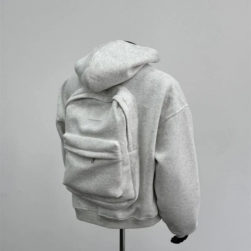 Man wearing a light gray hooded coat with a schoolbag design detail on the back.
