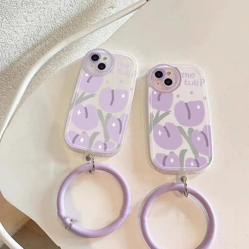 Clear purple tulip printed iPhone case with attached adjustable wrist strap on a table.