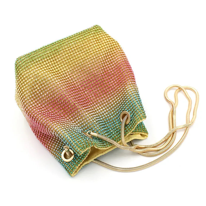 Soft rainbow rhinestone bucket handbag with adjustable strap on a white background.