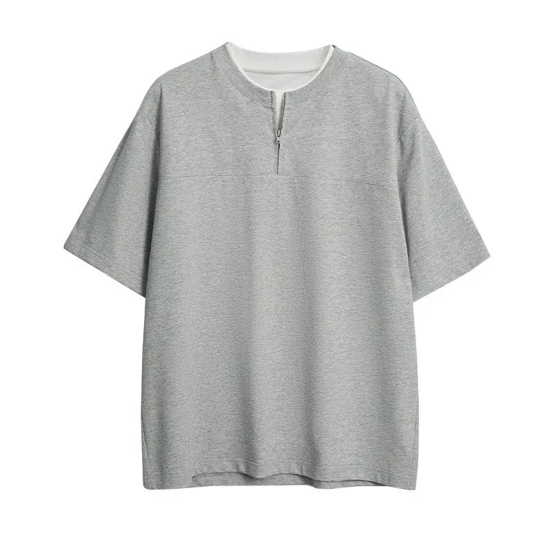 Loose blue zip-through patchwork top on a hanger, showing the false two-piece design and collar detail.
