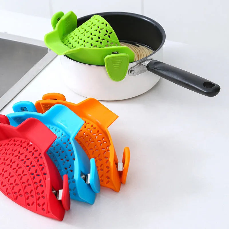 Green silicone pot rim drainer with stainless steel frame on a kitchen counter.