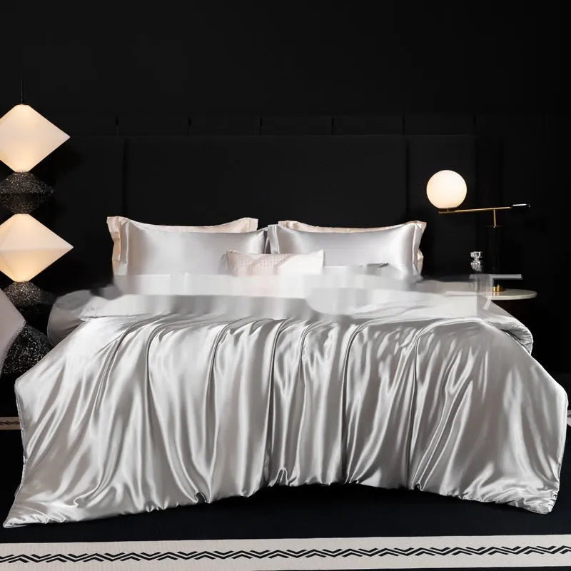 Silk bed sheet four-piece set in a solid colour displayed on a bed, showing fitted sheet and pillowcases.