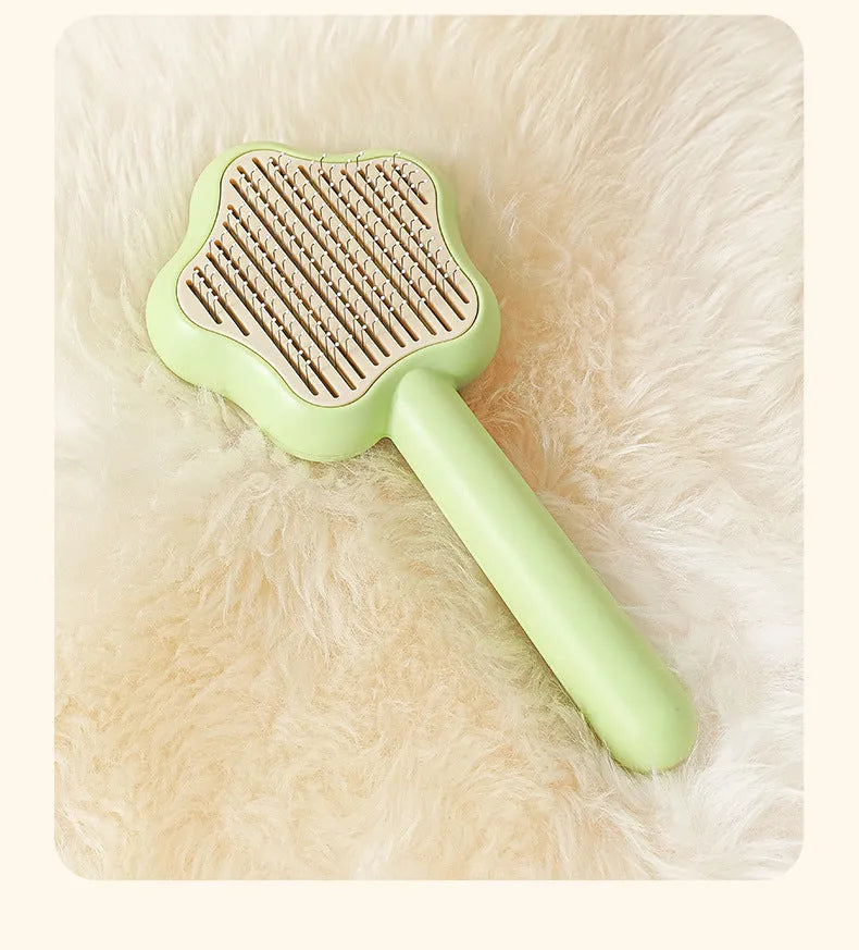 Green self-cleaning stainless steel cat comb for pet grooming on a white background