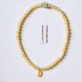 Women's hand-woven topaz bracelet with mantra barrel beads, square sugar beads, and fu charm in yellow jade