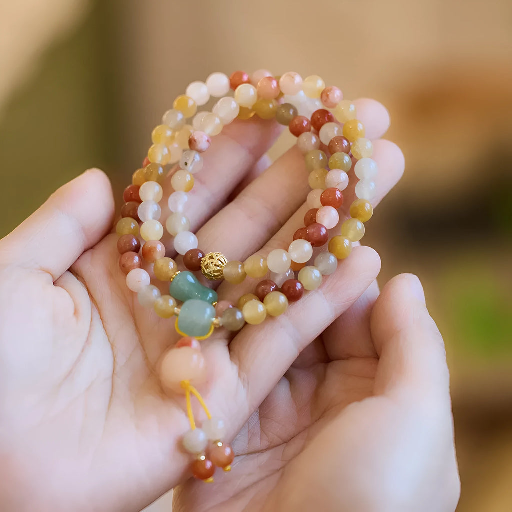 Women's handcrafted Jinsi Jade bracelet with pumpkin-shaped beads and tassels on a wrist.