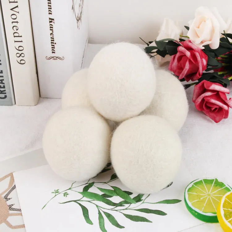 Set of wool laundry drying balls next to cotton storage bag for tumble dryers