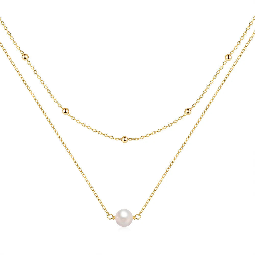 Close-up of a double-layer sterling silver necklace with twin pearl geometric pendants on a ball bead chain.