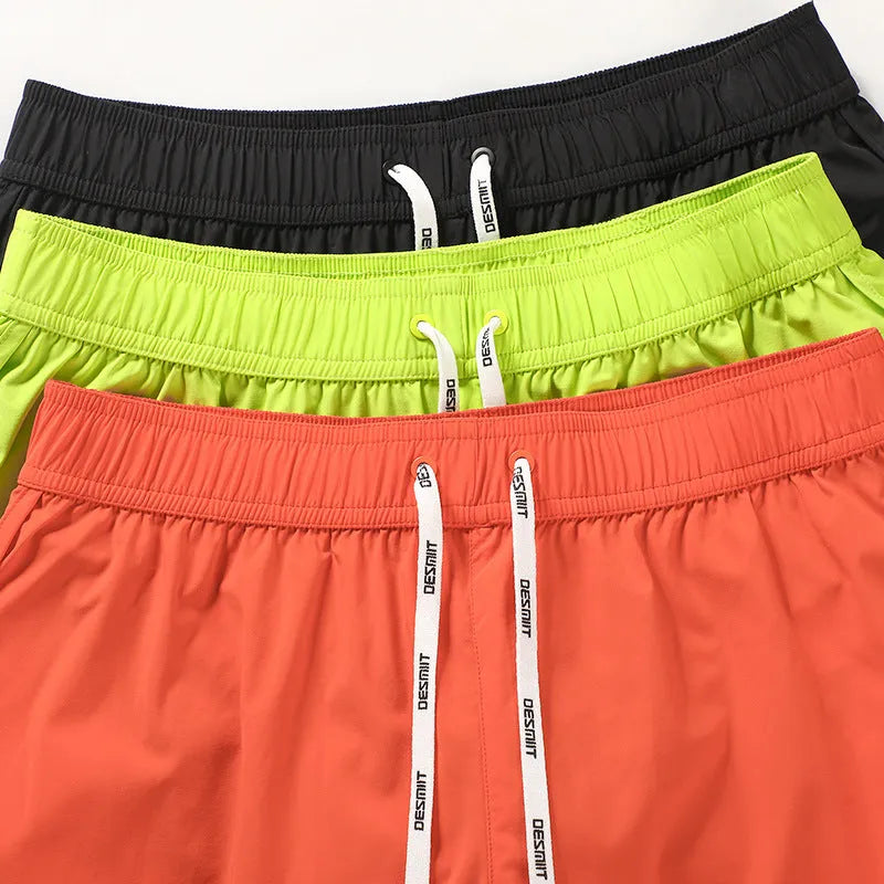 Man wearing orange micro-elastic polyester beach shorts for surfing or swimming.