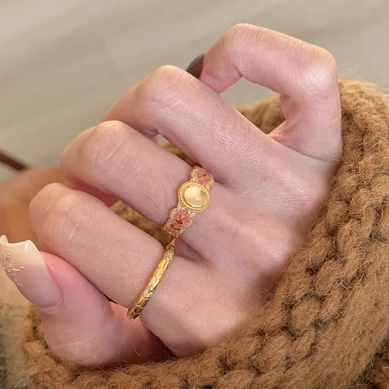 Close-up of a women's adjustable open ring with pink crystal enamel on a geometric gold-plated band.