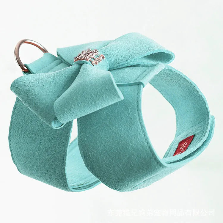 A pink microfiber dog harness with a bowknot on the chest strap, shown on a small dog.