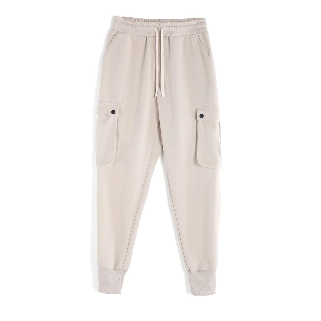 Man wearing loose-fit light grey cotton trousers with ankle ties and multiple pockets, suited for casual sports.