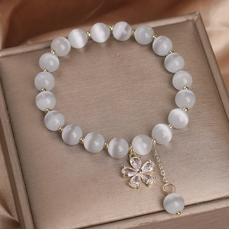 Single loop white cat's eye crystal bracelet with flower tassels and a morganite safety buckle pendant.