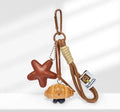 Handmade soda bread style handbag pendant with a cartoon design on a brown carrying strap.
