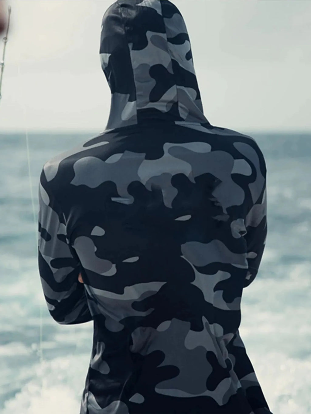 Man wearing a grey long sleeve fishing shirt with an integrated hood and face mask, showing mesh side panels.
