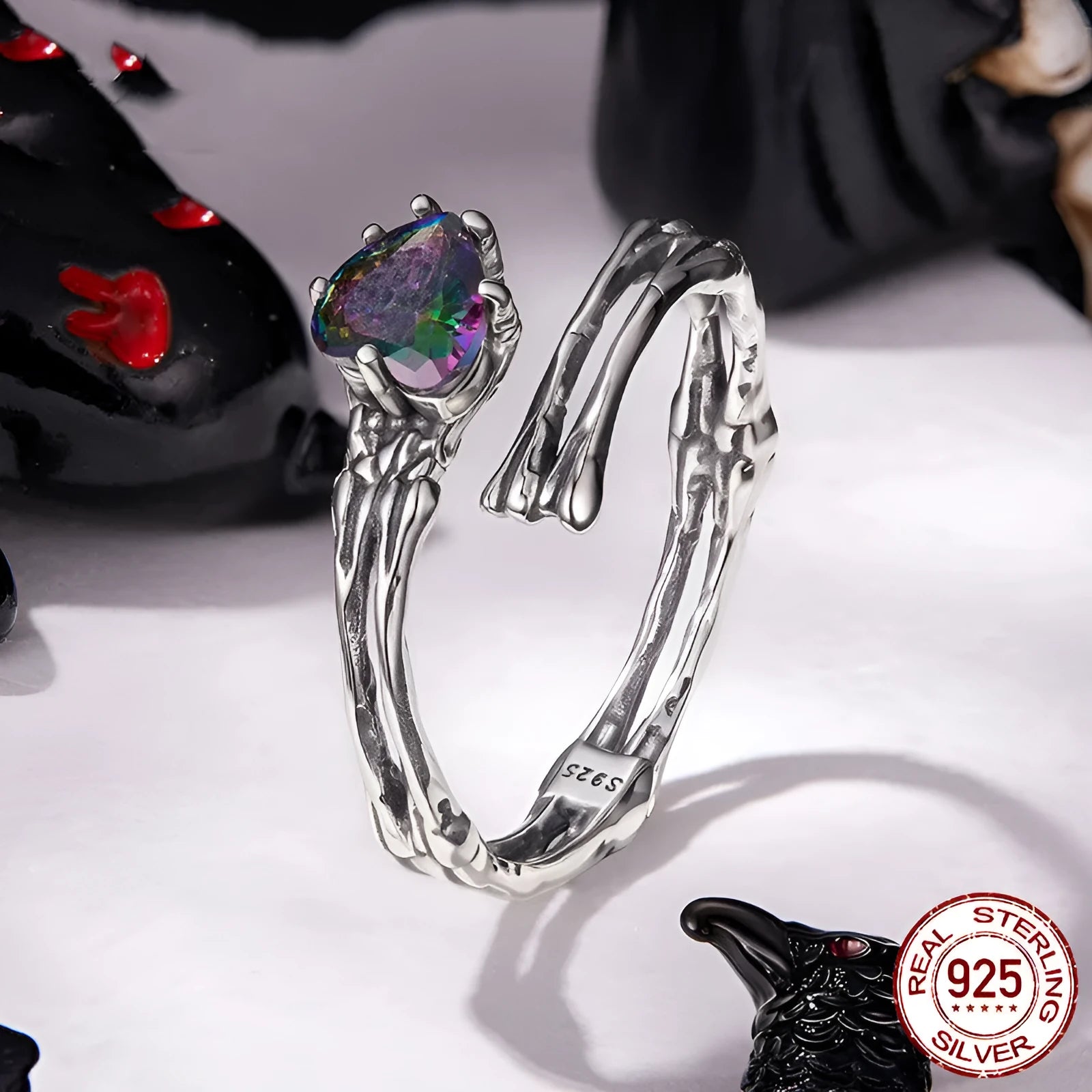 Adjustable silver skull hand ring with heart shaped base and pumpkin skull detail on white background
