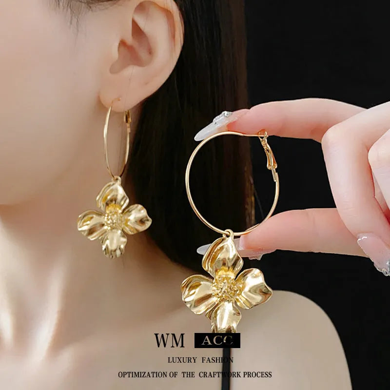 A pair of vintage-style metal earrings with a combined floral and geometric shape in a gold electroplated finish.