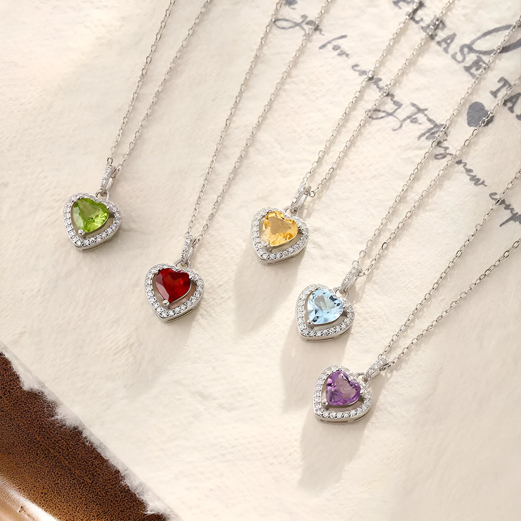 Women's sterling silver heart necklace with a natural gemstone on an adjustable cross chain.