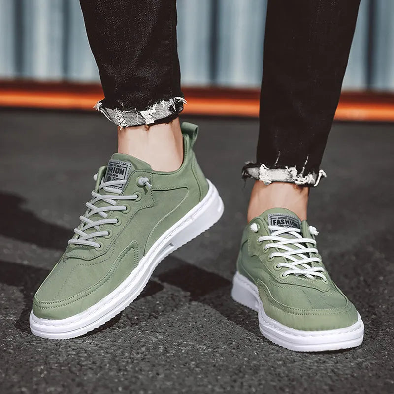 Men's green canvas lace-up sneakers with round toe, flat heel, and letter print side detail on a white background