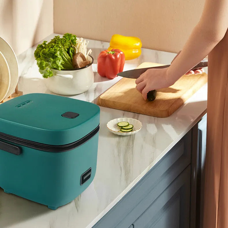 Green mini rice cooker 1.2L with steaming plate, rice spoon and measuring cup on countertop