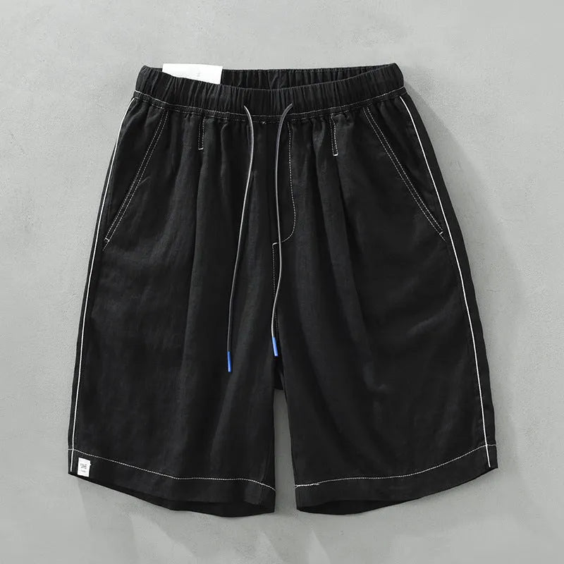 Man wearing loose fit green linen shorts with a straight leg and drawstring waist for casual summer wear.