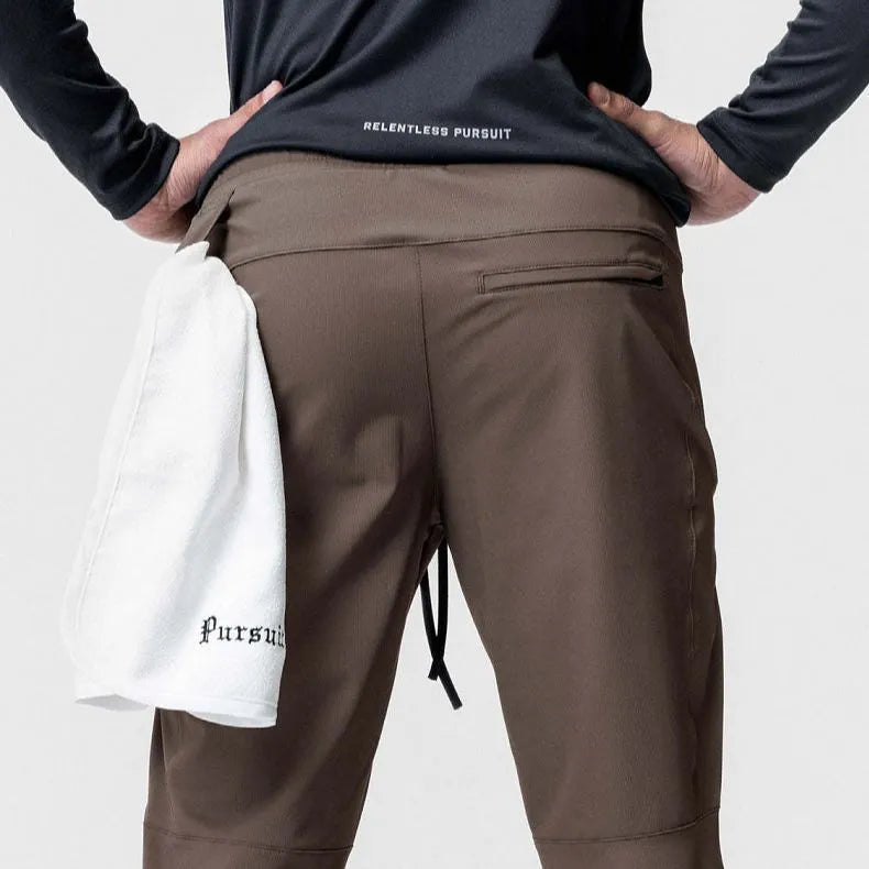 Men's grey loose-fit fitness trousers with ankle ties, made from quick-drying polyester fabric.