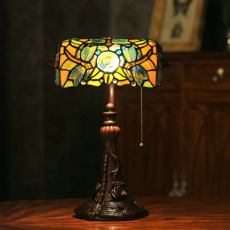 Tiffany-style desk lamp with a coloured stained glass shade on a resin base.