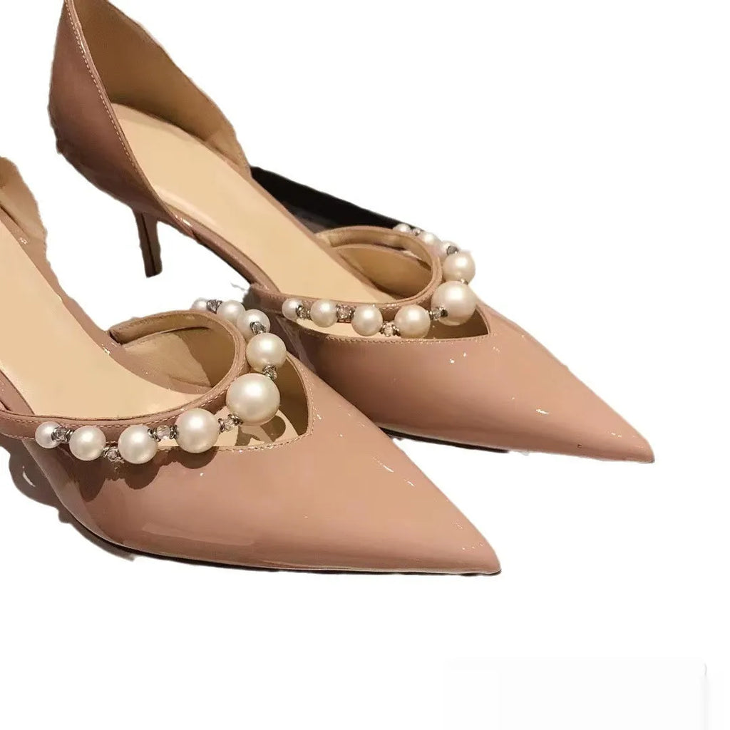 Black pointed toe patent leather women's stiletto heels with pearl decoration on the heel.