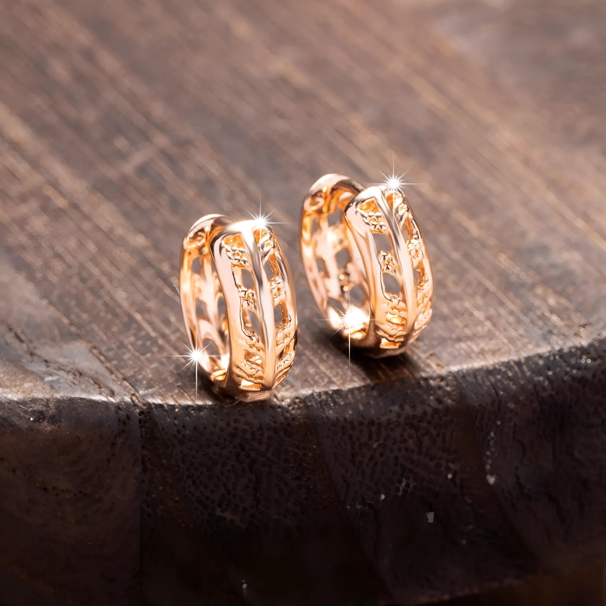 Close-up of rose gold plated copper stud earrings with hollow leaf and heart shapes on a grey background.