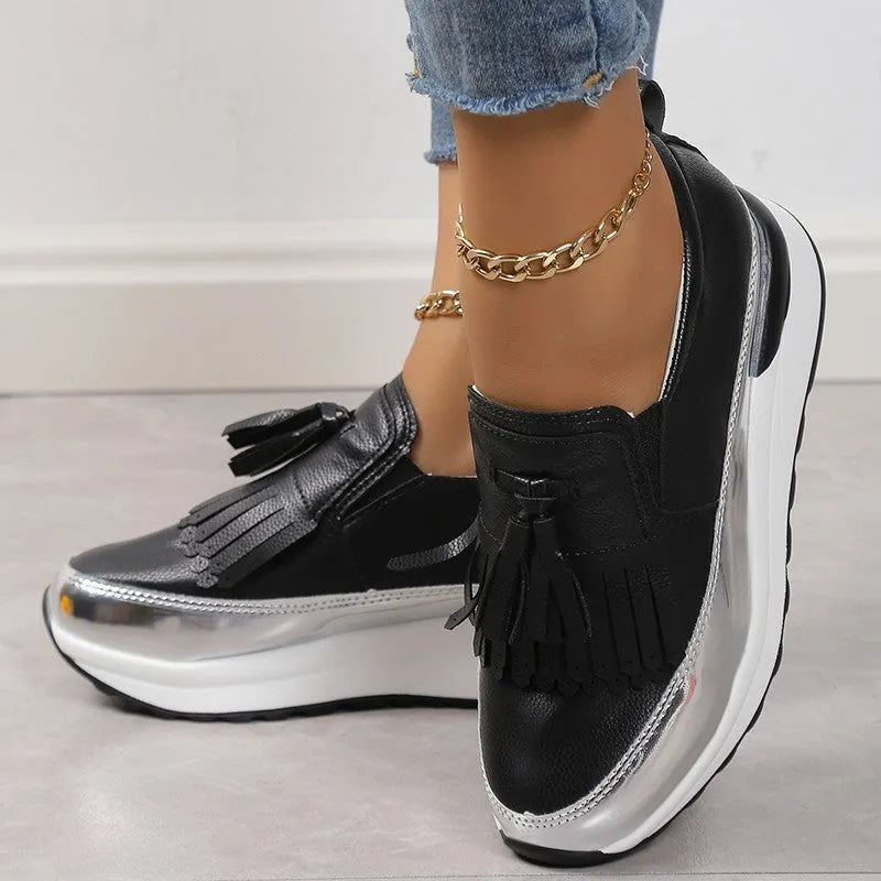 Women's black casual platform shoes with tassel detail and muffin wedge heel on a white background