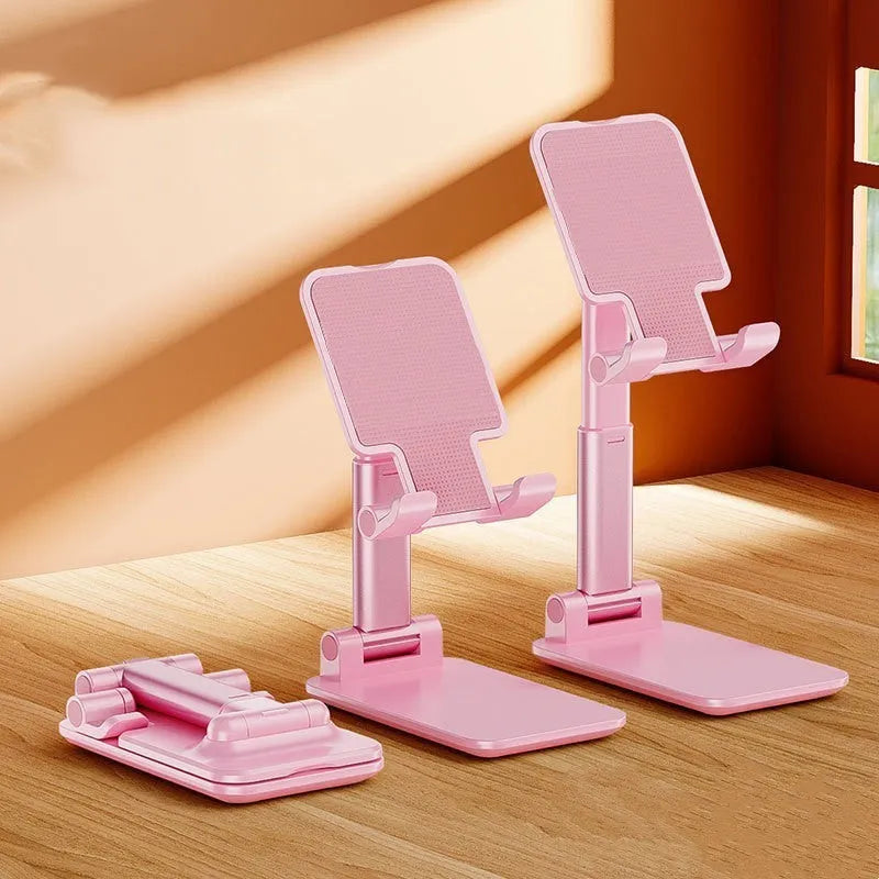 White folding telescopic mobile phone holder with silicone pad on a desktop, holding a smartphone at an angle.