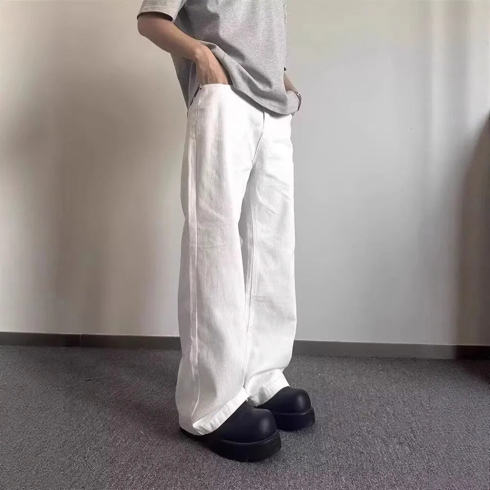A pair of men's loose-fit white straight-leg cotton jeans on a plain background.