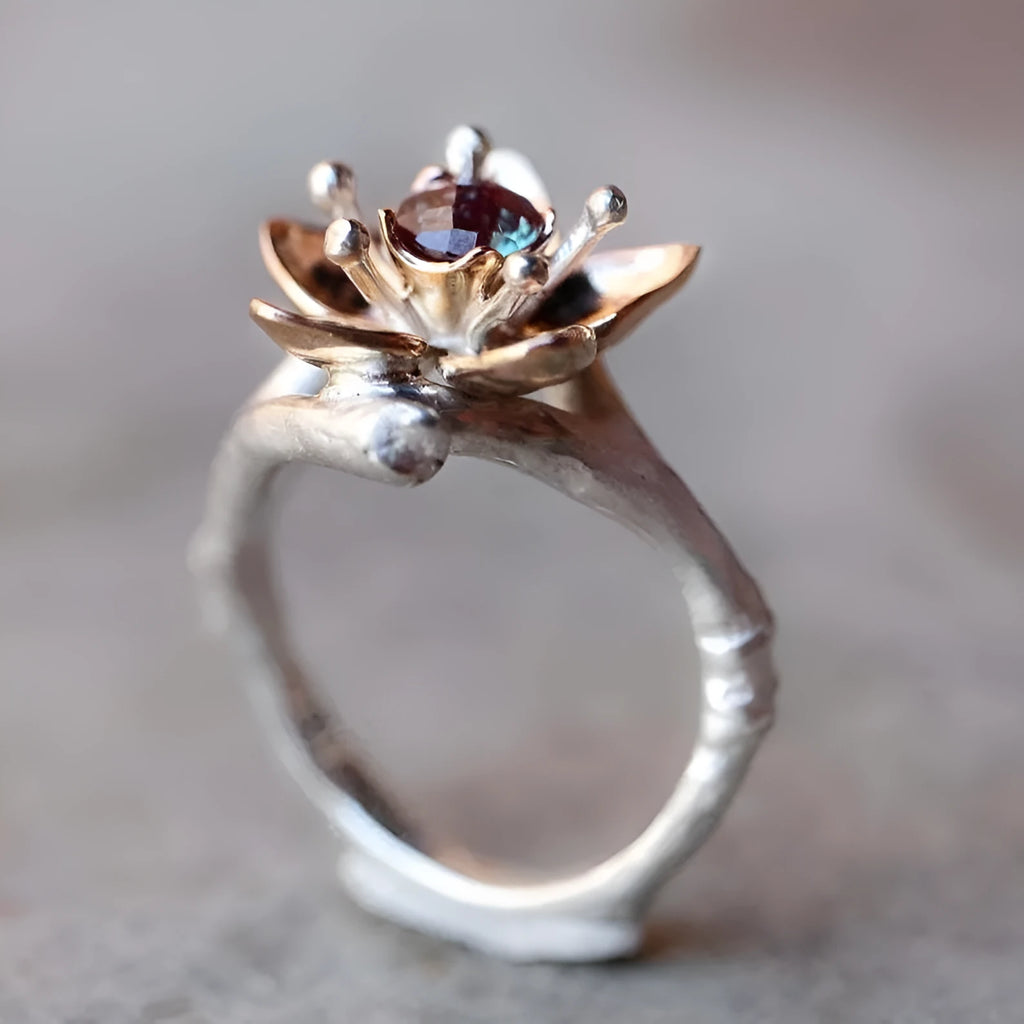 Silver-tone women's ring with two-tone floral and geometric design on a hand.