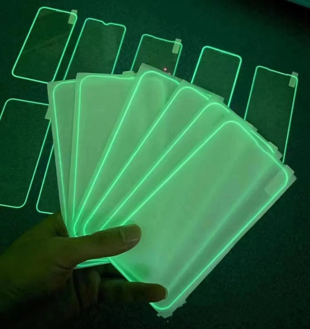 Fluorescent pink luminous tempered glass screen protector applied on an iPhone 13, glowing softly in a dark setting.