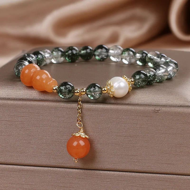 Green phantom quartz crystal bracelet with pearl and rhinestone accents on women's wrist
