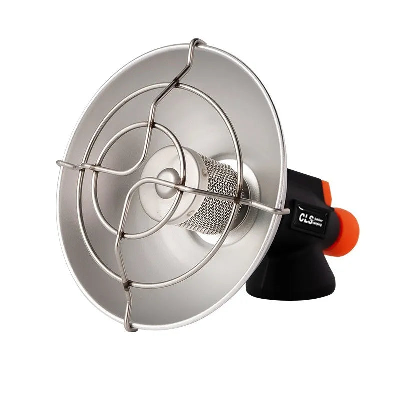 Black and orange mini portable camping stove with automatic ignition on a grassy outdoor surface.