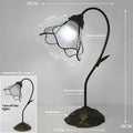 Retro American classical desk lamp with a decorative glass shade on a table.