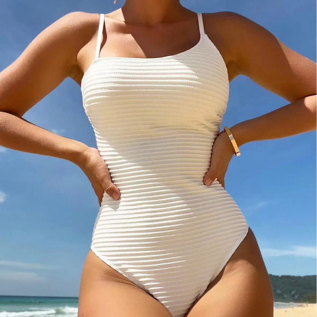 Women's solid colour conservative one-piece swimsuit with spaghetti straps on a neutral background.