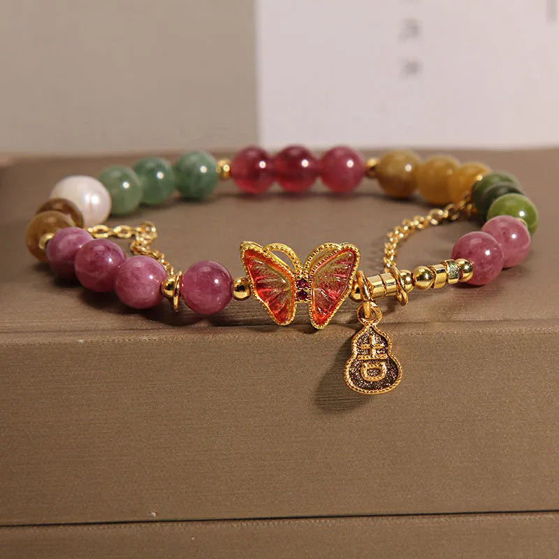 Close-up of a jade and tourmaline coloured agate bracelet with a butterfly-shaped gourd charm.