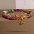 Close-up of a jade and tourmaline coloured agate bracelet with a butterfly-shaped gourd charm.