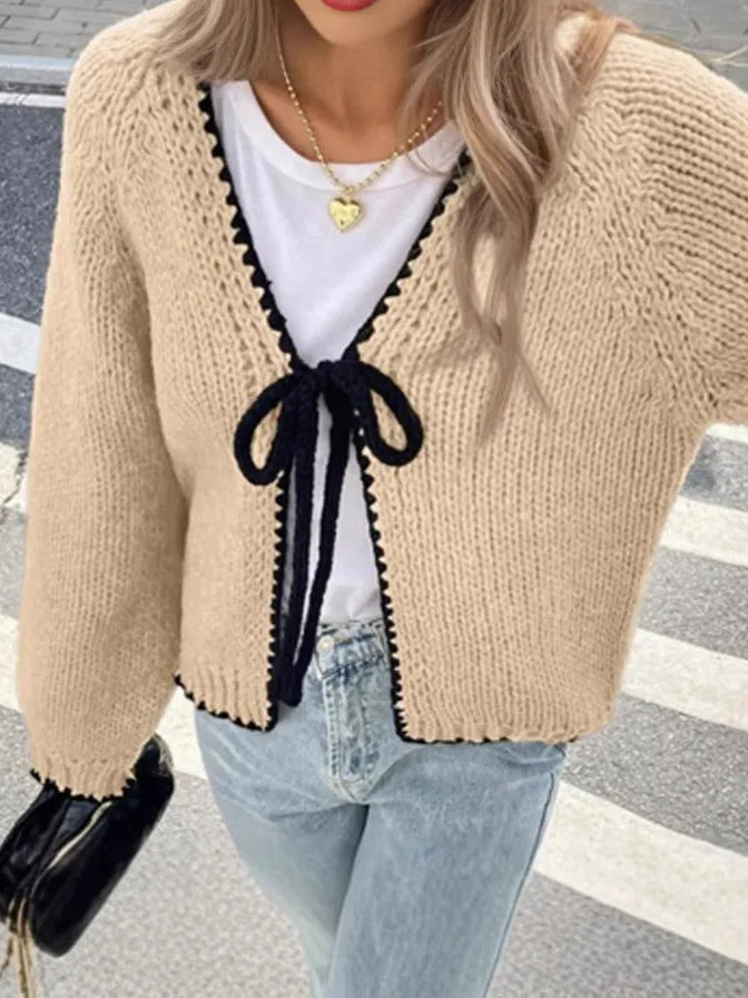 A solid colour loose-fit cardigan with long sleeves and small crochet flower details on the front.