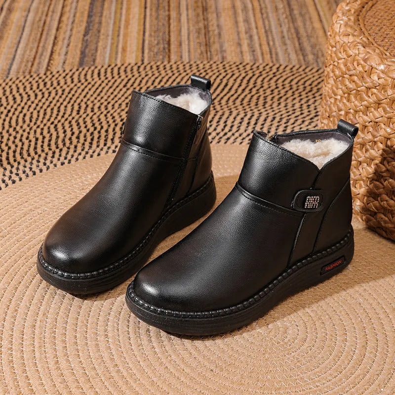 Pair of black cowhide ankle boots with side zipper, platform mid heel, and wool fleece lining visible at the top.