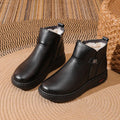 Pair of black cowhide ankle boots with side zipper, platform mid heel, and wool fleece lining visible at the top.