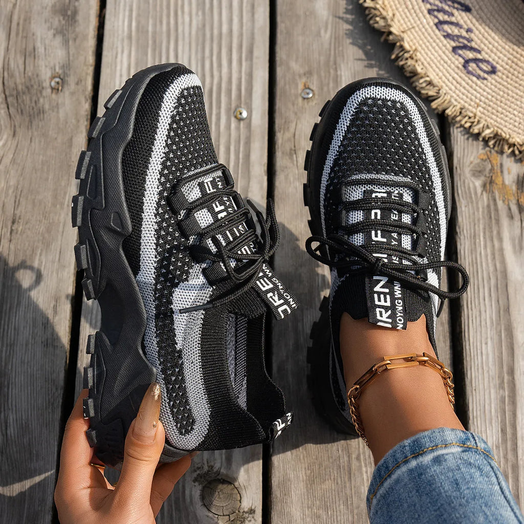 Women's Flyknit mesh lace-up sneakers in a grey colourway with a round toe and flat rubber sole.