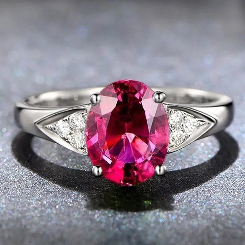 A women's court style ring with a natural zircon stone, shown in red and blue, featuring heart and bell-shaped inlay patterns.