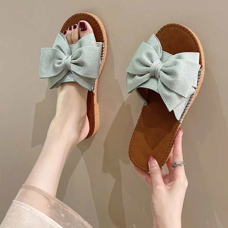 Women's beige suede slip-on sandals with a flat heel and soft bottom on a light background